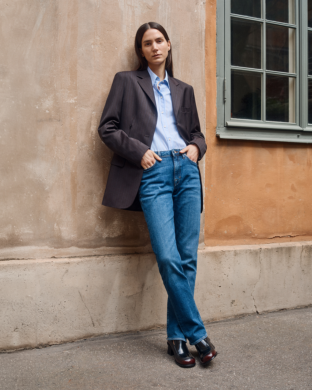 Woman in brown tailored blazer, blue cotton shirt and blue denim jeans