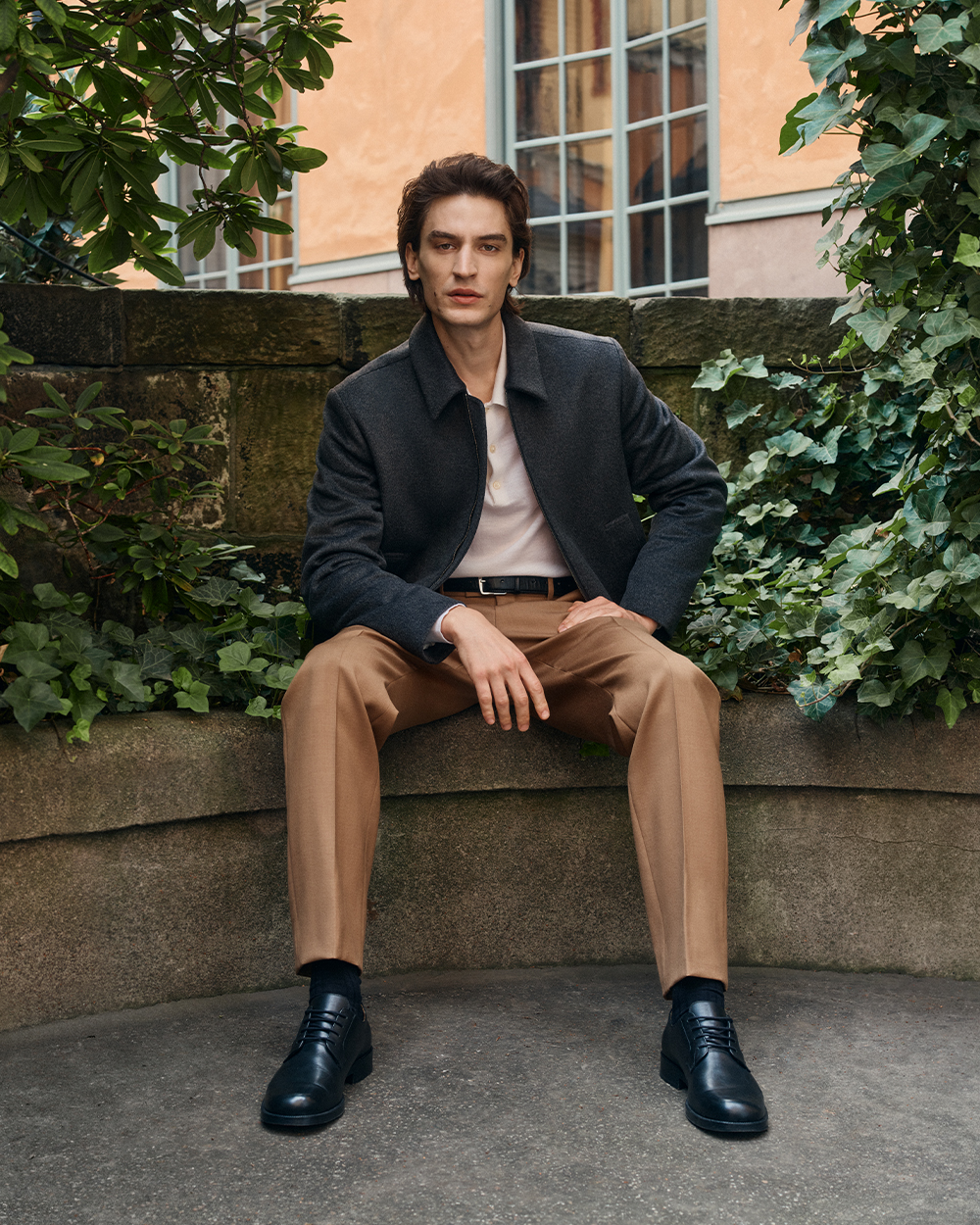 Man in grey jacket, beige suit trousers and black dressed shoes