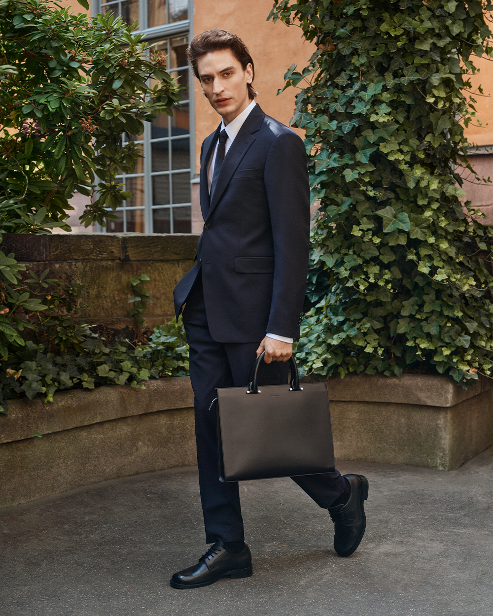 Man in dark blue tailored suit with black briefcase