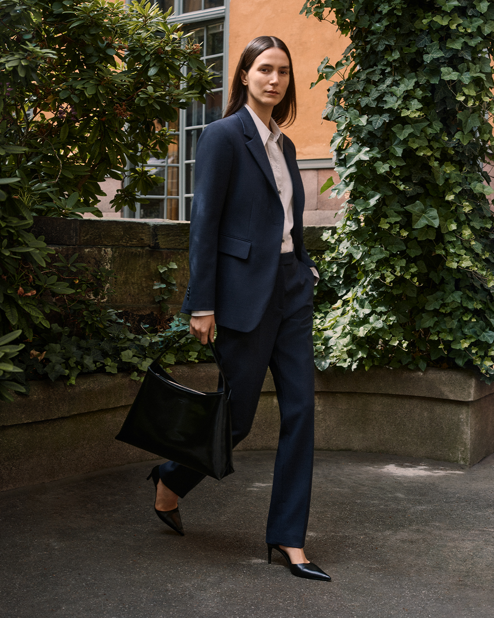 Woman in dark blue tailored suit with black bag